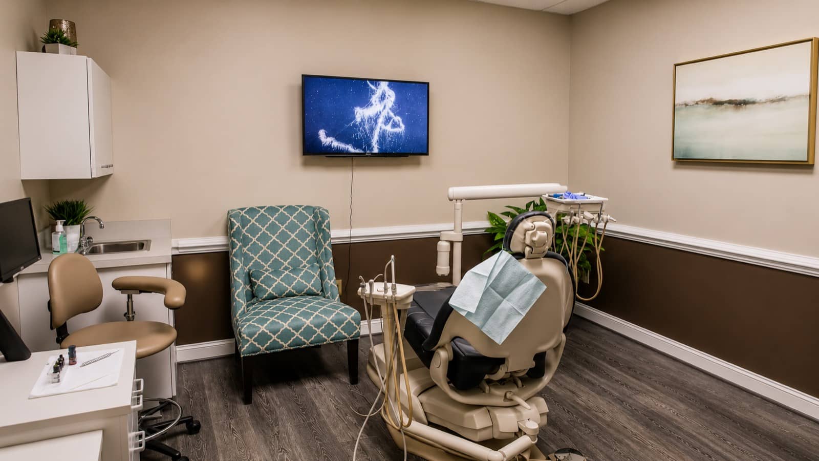 Calm dental operatory with abstract landscape art and a green accent chair
