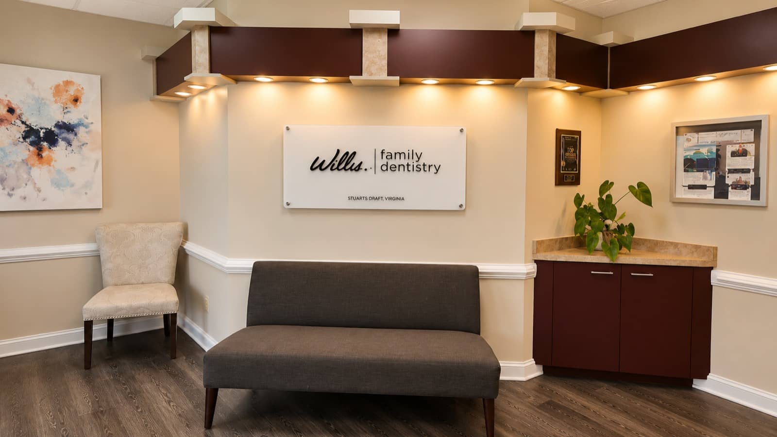 Reception lounge at Willis & Associates Family Dentistry - Stuarts Draft with a sofa, plant, and brand sign